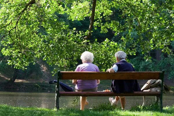 Seniorenpaar auf Bank am See im Park Stockfoto