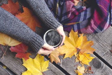 Sonbahar, Ekim ayının sarı yapraklarının arka planında çay ya da kahve içer. Sonbahar konforu ve ruh hali konsepti.