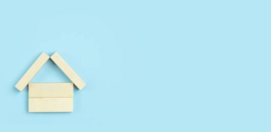 Ev konsepti. Satın alma, kira, satış, ticari ve iş ilişkileri, gayrimenkul inşaatı. Mavi arka planda ahşap bir ev.