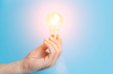 Bilgi ve fikir kavramı. Boş mavi bir arkaplanda elinde lamba olan ampul. Beyin, bilgelik, bilgi ve enerji korunumu yaratıcı bir fikirdir. Yüksek kalite fotoğraf