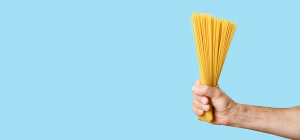 Massa de espaguete na mão em um fundo de banner em branco. Esparguete italiano cru antes de cozinhar e comer comida italiana — Fotografia de Stock