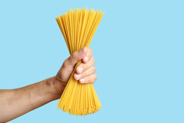 Massa de espaguete na mão em um fundo em branco. Esparguete italiano cru antes de cozinhar e comer comida italiana — Fotografia de Stock