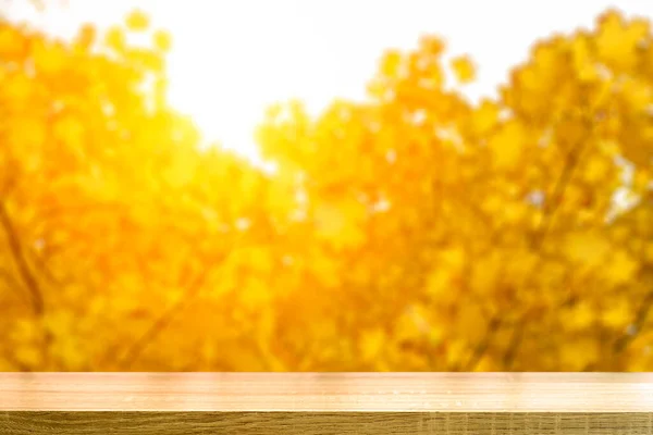 Sfondo tavola autunno. Tavola dei prodotti in legno con fogliame giallo dorato autunnale sfumato nel soleggiato giorno di ottobre sullo sfondo. — Foto Stock