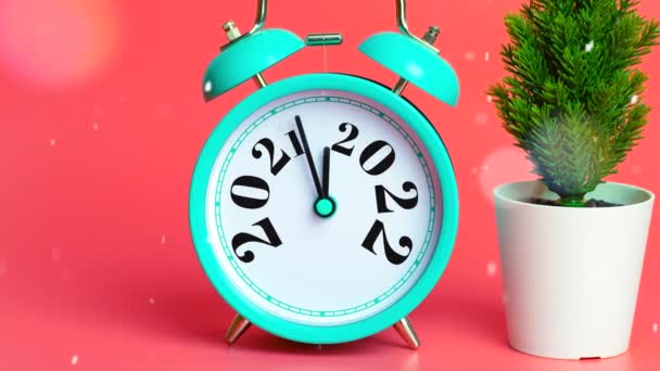 Glad nyårsafton jul 2022 bakgrund. Minimalt nyårskort koncept. väckarklocka, julgran och festligt glitter på en rosa bakgrund. — Stockvideo