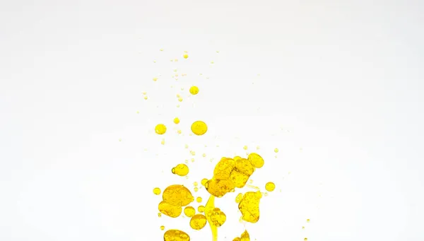 Οι σταγόνες πετρελαίου απομονώθηκαν. Χρυσές σταγόνες λαδιού σε νερό σε λευκό φόντο. Συστατικά τροφίμων ή καλλυντικών. — Φωτογραφία Αρχείου