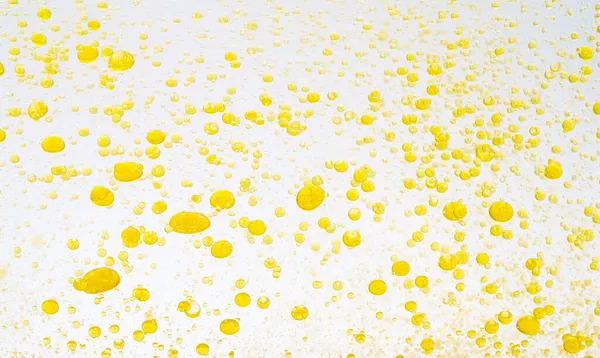 Gotas de aceite aisladas. Gotas líquidas doradas de aceite en agua sobre un fondo blanco. Componentes alimentarios o cosméticos. —  Fotos de Stock