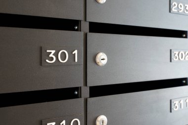 Mektuplar ve yazışmalar için posta kutuları. Konut veya ofis lobisinde numaraları olan modern siyah posta kutuları