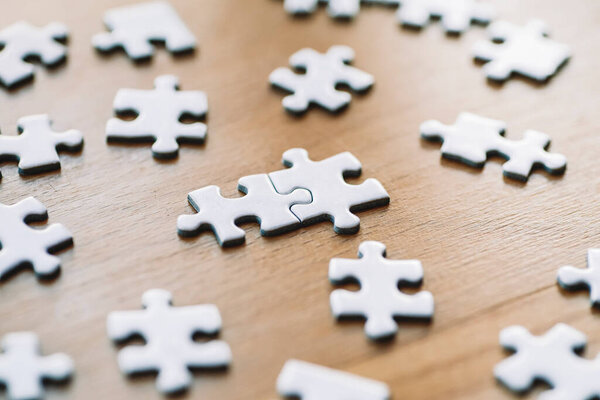  Puzzle pieces are connected. White puzzle pieces on a wooden table background. Business, partner, solution, alliance, union concept.