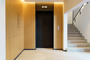 Bir apartmanın lobisindeki asansör. Modern dekor ve ahşap zemin ve girişi tamamlıyor..