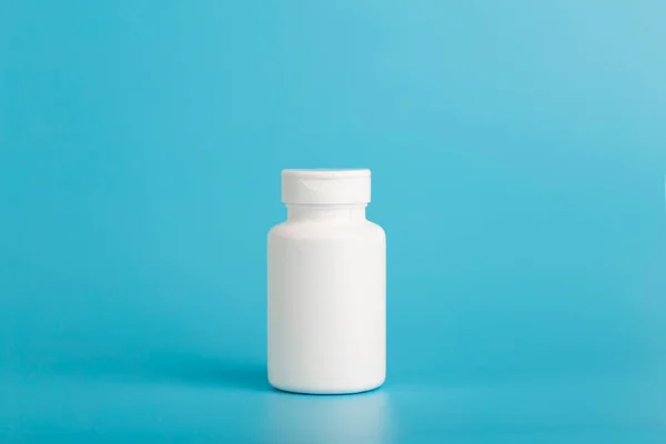 En burk piller isolat. Vit plastburk för medicinska piller, droger och vitaminer på en tom blå bakgrund. — Stockfoto