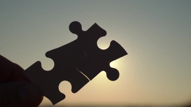 I pezzi di puzzle sono collegati. Puzzle pezzi in mano su uno sfondo cielo soleggiato. Business, partner, soluzione, alleanza, concetto sindacale. — Video Stock