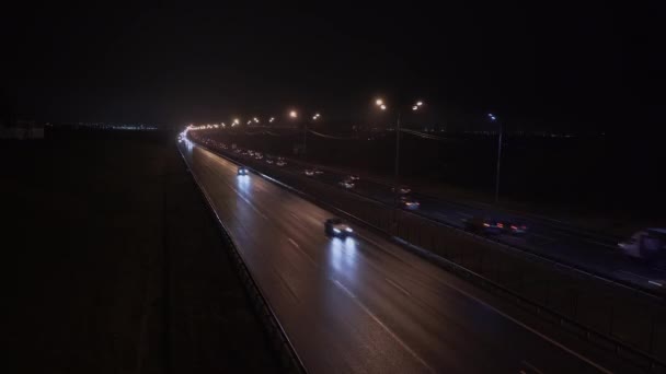Trânsito noturno em uma estrada da aldeia fora da cidade. Vista à noite iluminação rodoviária e tráfego de movimento rápido — Vídeo de Stock
