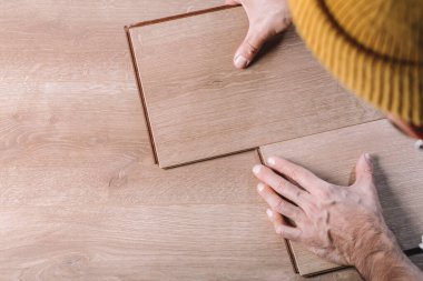 Bir odaya ya da ofise kaplama döşeme kuruluyor. Bir işçinin elinde tahta parke tahtalar. İnşaat ve dekoratif çalışmalar konutların bitirilmesi için