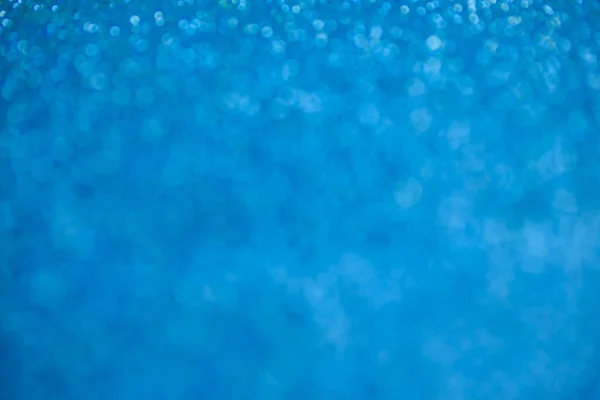 Fondo azul brillo. Lámina de textura y confeti bokeh, luz de polvo azul. Fiesta festiva Navidad y año nuevo fondo víspera. — Foto de Stock