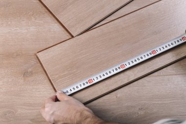 Bir odaya ya da ofise kaplama döşeme kuruluyor. Bir işçinin elinde tahta parke tahtalar. İnşaat ve dekoratif çalışmalar konutların bitirilmesi için