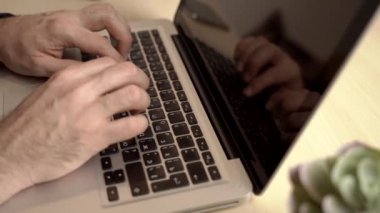 Adam ofiste ya da internette bir bilgisayar için çalışıyor. Eller masaüstünde dizüstü bilgisayarın arkasında. Yazma, yazma, internet, teknoloji konsepti.