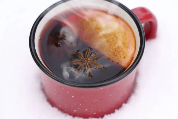 Вино или чай на снежном фоне во время снегопада в лесу. Зимние горячие напитки с ароматическими специями корицы, кардамона и апельсина. Тепло, комфорт и атмосфера декабрьской природы и — стоковое фото