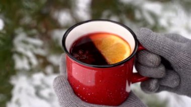 Bardakta sıcak şarap. Şarap, baharat ve tarçına dayalı sıcak bir Noel içeceği. Kışın kokteyl içen kız. Doğada soğuk karlı orman.