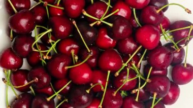 Kirazlar mavi arka planda bir tabakta döner. Bir sürü olgun vişne suyu. Vitaminler, vejetaryen, meyve yiyeceği video konsepti