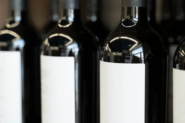 Botellas de vino con etiquetas en blanco en el mostrador de una licorería. Fondo del vino. Enfoque seleccionado —  Fotos de Stock