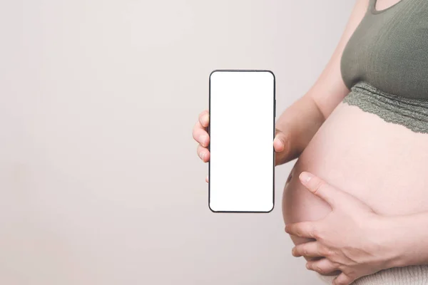 Pregnant woman holding a phone with a blank screen, mock-up. Pregnancy apps, gadgets, move and push tracking, diet background — Stock Photo, Image