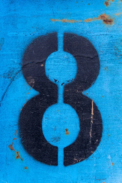 Numer 8 w czarnej farbie na starej niebieskiej powierzchni żelaza z rdzą i śladami brudu. — Zdjęcie stockowe