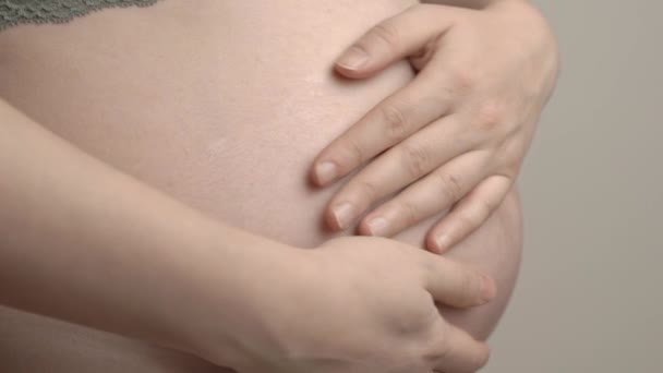 Ciężarna kobieta głaska dziecko po brzuchu. Ciąża i ochrona kobiecego ciała i zdrowia podczas porodu. — Wideo stockowe