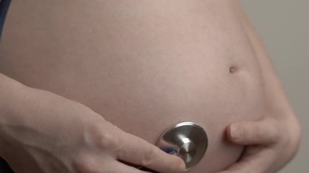 Hamile kadın bebeğin kalp atışlarını ve hareketlerini steteskop, fetoskop ya da Pinard Horn ile dinliyor. Doğum öncesi fetüs sağlığı, endişe, korku konsepti — Stok video