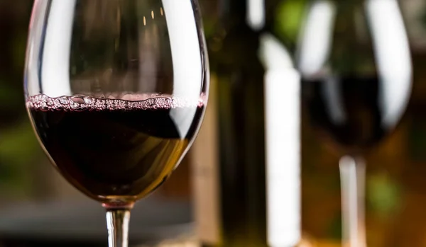 Degustación de vinos. Una copa de vino tinto en el fondo de una mesa de restaurante con botella en una cena o fiesta. —  Fotos de Stock