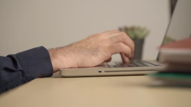 穿着可笑的袜子和睡衣，在家里的笔记本电脑前工作。一个男人穿着家居服坐在桌子旁的键盘上打字。远程学习或工作概念. — 图库视频影像