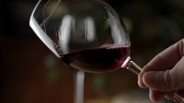 Bir kadeh kırmızı şarap. Şarap tatma bir restoranın ya da barın ahşap masasının arka planında bir bardağa dökülüyor. Tat, aroma, zenginlik. Üzüm hasadı konseptinden alkollü içecekler. Yüksek kalite