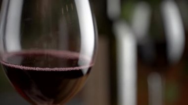 Bir kadeh kırmızı şarap. Şarap tatma bir restoranın ya da barın ahşap masasının arka planında bir bardağa dökülüyor. Tat, aroma, zenginlik. Üzüm hasadı konseptinden alkollü içecekler.