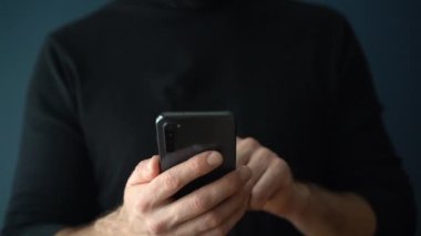 Akıllı telefon kullanıyor. Genç bir erkek müteahhit stüdyodaki telefonu boş bir duvarın arka planında kullanıyor. İnternet araması, iletişim, ağ, ileti kavramı