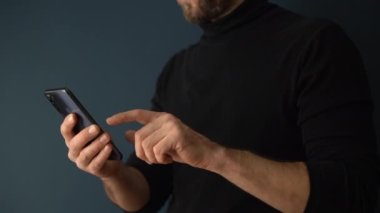 Akıllı telefon kullanıyor. Genç bir erkek müteahhit stüdyodaki telefonu boş bir duvarın arka planında kullanıyor. İnternet araması, iletişim, ağ, ileti kavramı