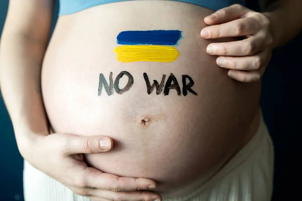 Війна в Україні, український конфлікт. Прапор України малює на животі вагітної жінки. Мир, пацифізм, активізм, війна та підтримка. — стокове фото