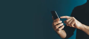 Boş bir arkaplanda genç bir adamın akıllı telefonunu kullanmak. İnternet 'i, kuryeyi, alışverişi, iletişimi kullanırken telefon elinde. Teknoloji, uygulamalar, iş konsepti.
