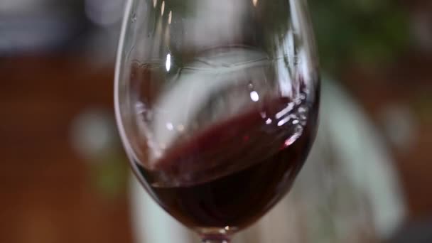 Un verre de vin rouge. Dégustation de vin versant un verre sur le fond d'une table en bois d'un restaurant ou d'un bar. Goût, arôme, richesse. Boissons alcoolisées issues du concept de vendange. — Video
