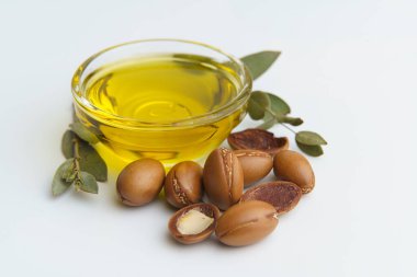 Argan tohumları ve yağı beyaz arka planda izole edilmiş. Bitkili Argan yağı fındığı. Kozmetik ürünleri ve doğal yağlar