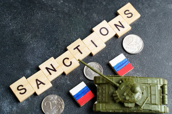 Concepto de sanciones contra Rusia. Tanque de juguete, rublos y la inscripción Sanciones sobre un fondo oscuro. Conflicto de guerra en Ucrania, impago, crisis económica y monetaria en Rusia. — Foto de Stock