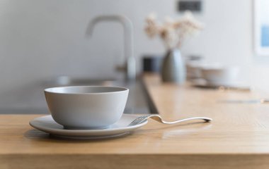 Mutfak evindeki ahşap masada çatal ve yiyecekle seramik beyaz kase. Mutfak tasarım konsepti.