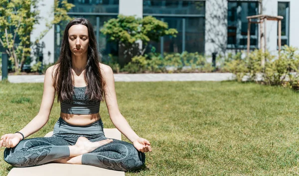 Bir kadın nilüfer pozisyonunda meditasyon yapar ve yaz güneşli havalarda parkta dinlenir. Yoga, akıl sağlığı, rahatlama, sağlık konsepti. Yüksek kalite fotoğraf