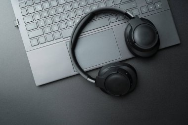 Kulaklıklar ve dizüstü bilgisayarlar siyah masaüstünde. Müzik, ses, ses konsepti. Yüksek kalite fotoğraf