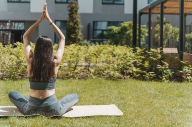 Yogadaki kadın parkta ya da bahçede poz veriyor. İnce bir Avrupalı kız yaz güneşli havalarda vücudun iyileşmesi ve gelişmesi için Hint yogasında pratik yapmakla meşgul. Sağlık