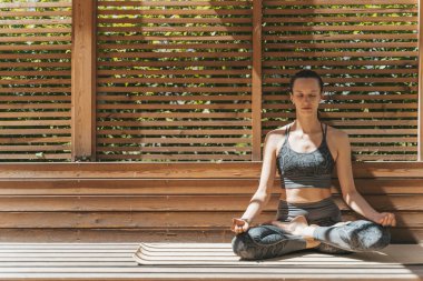 Bir kadın nilüfer pozisyonunda meditasyon yapar ve yaz güneşli havalarda parkta dinlenir. Yoga, akıl sağlığı, rahatlama, sağlık konsepti. Yüksek kalite fotoğraf