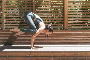 Yogadaki kadın parkta ya da bahçede poz veriyor. İnce bir Avrupalı kız yaz güneşli havalarda vücudun iyileşmesi ve gelişmesi için Hint yogasında pratik yapmakla meşgul. Sağlık