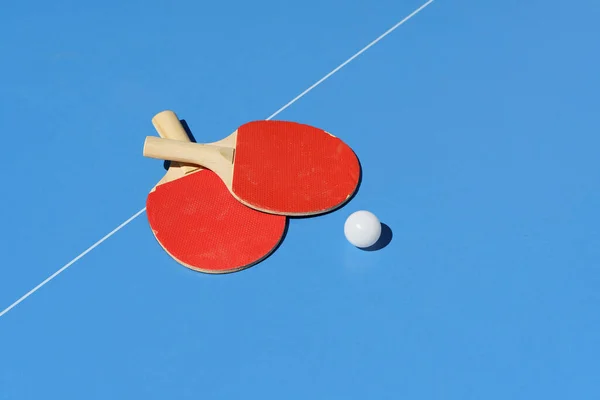 Ping pong tennis table background. Tennis rackets and a ball on a blue sports table. High quality photo