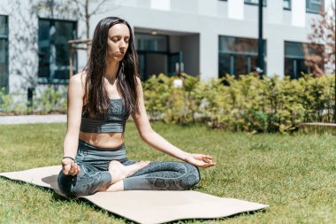 Bir kadın nilüfer pozisyonunda meditasyon yapar ve yaz güneşli havalarda parkta dinlenir. Yoga, akıl sağlığı, rahatlama, sağlık konsepti. Yüksek kalite fotoğraf