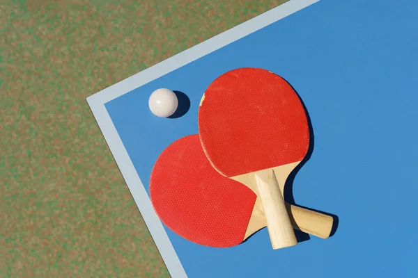 Ping pong tennis table background. Tennis rackets and a ball on a blue sports table. High quality photo