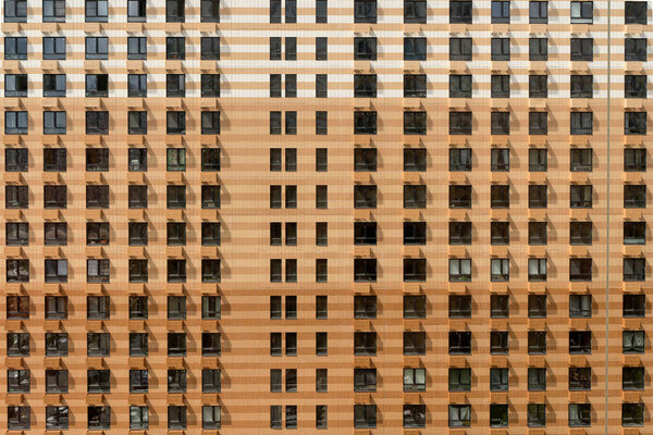 Facade of a new multi-apartment high-rise residential building with windows background. Architecture and design of a typical development of a new city district. Construction, developer, housing