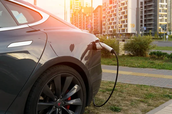 Minsk, Belarus - August 12, 2022: Tesla car charges the electric motor at the charging station on the street. Electric cars, ecology, transport concept. High quality photo